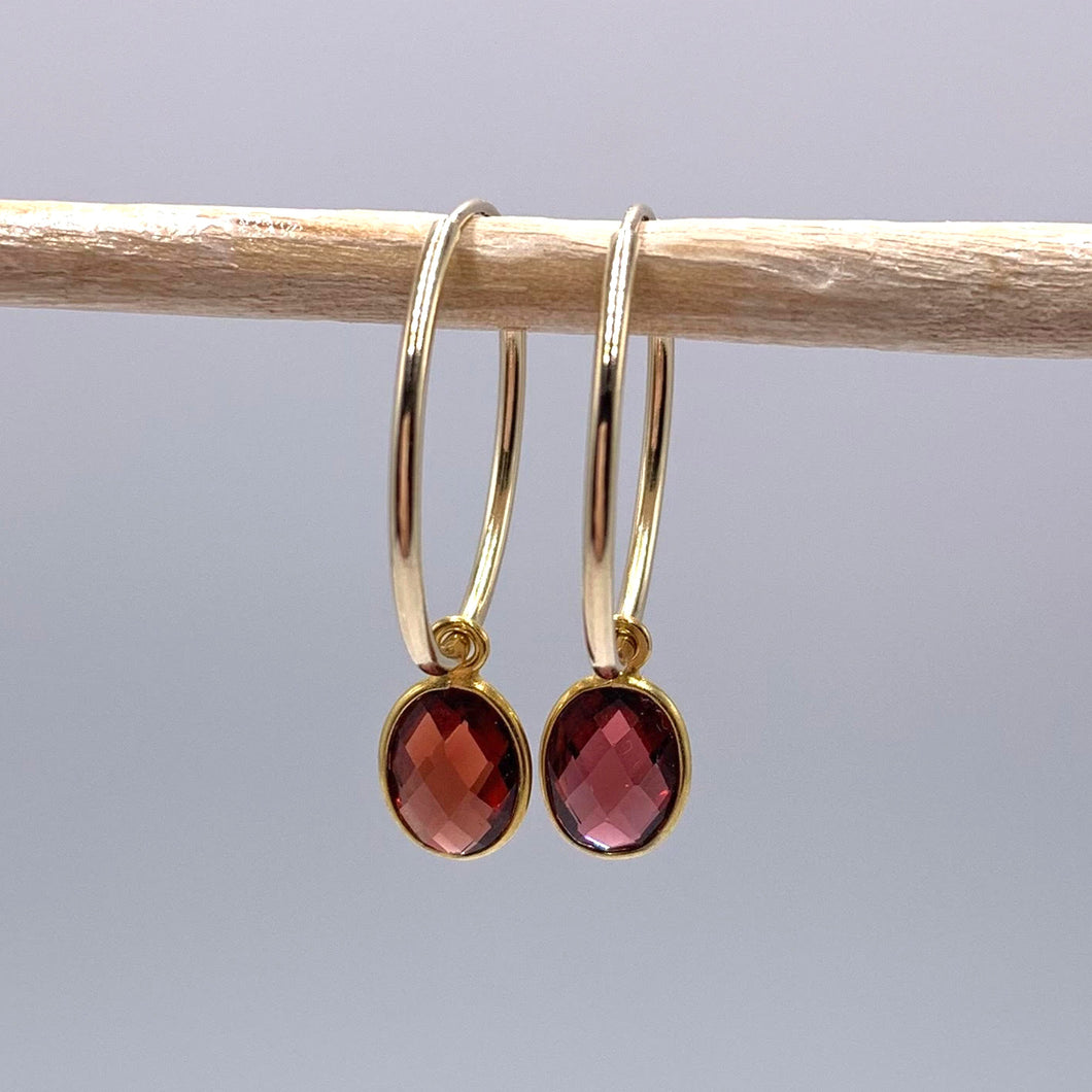Gemstone earrings with garnet (dark red) oval crystal drops on gold medium hoops