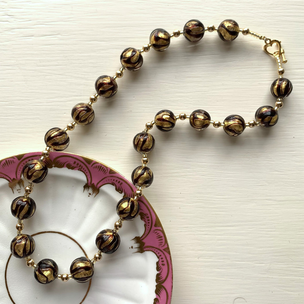Necklace with black appliqué over gold Murano glass sphere beads on gold