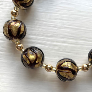 Necklace with black appliqué over gold Murano glass sphere beads on gold
